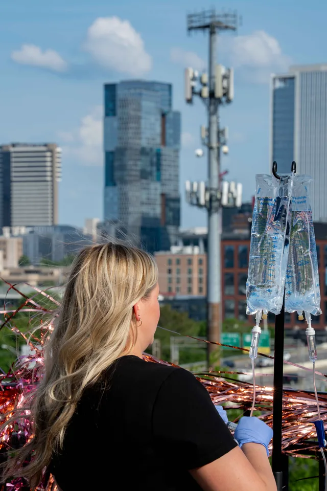 A Drip Lab nurse gets an IV ready on a Nashville rooftop with the downtown skyline behind her